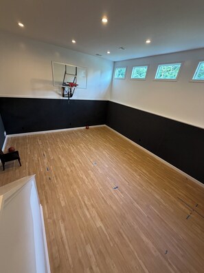 A basketball court with a hoop, wooden flooring, and a bench. - Tranquil luxurious 4-bedroom home on a scenic 2.5 ace lot, min. from Penn State. (Port Matilda)