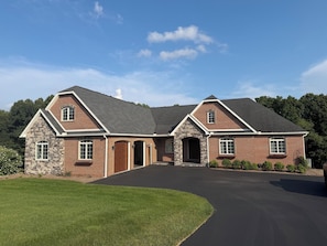 A two-story brick house with a stone facade, a driveway, and a well-maintained lawn.