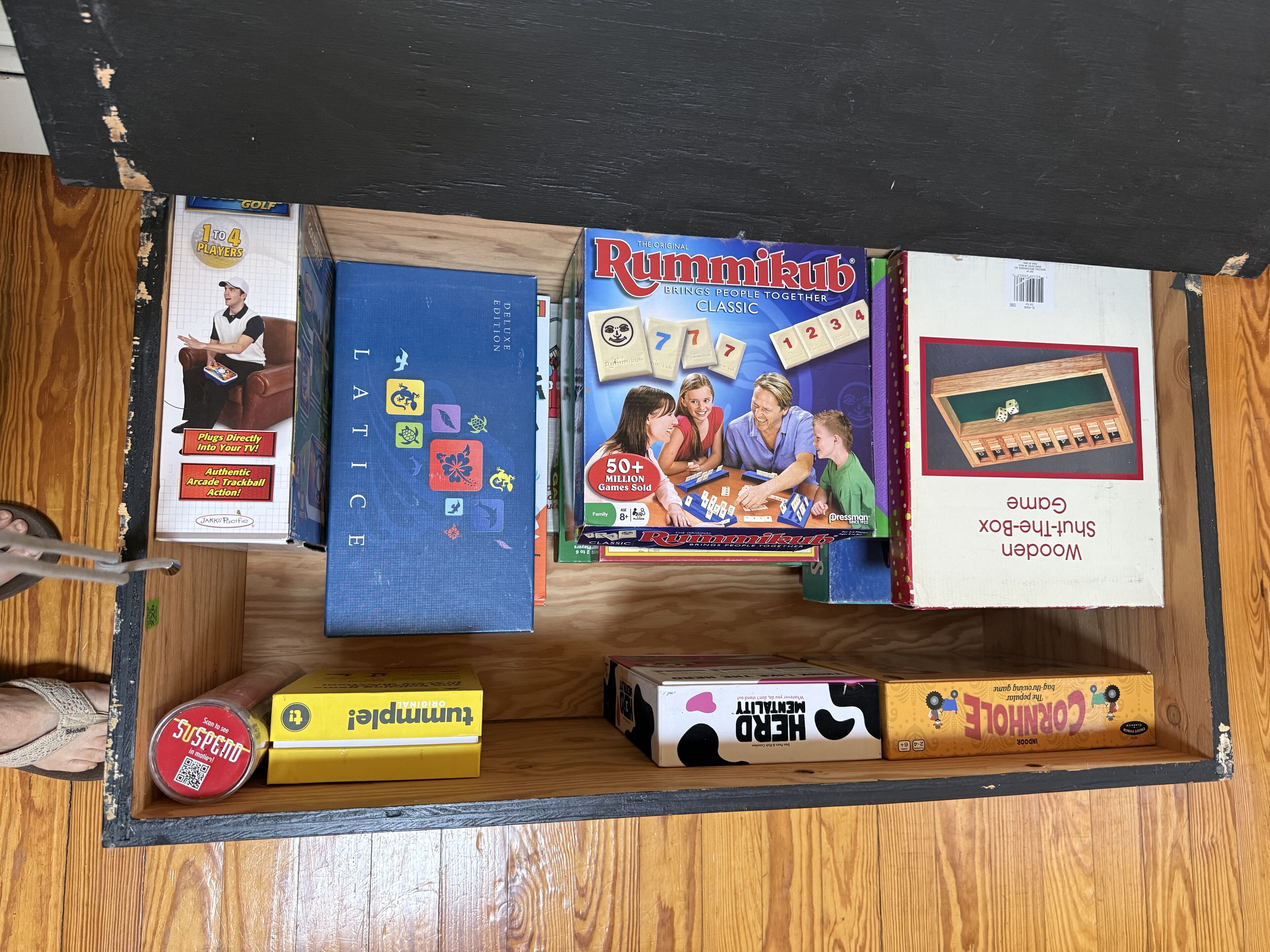 Een lade gevuld met verschillende gezelschapsspellen, waaronder LATIC, Rummikub en Corgi.