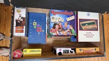 Een lade gevuld met verschillende gezelschapsspellen, waaronder LATIC, Rummikub en Corgi.