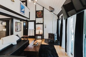 A cozy living room with a sofa, a wooden table, and a fireplace. - Cozy Sunriver Retreat - SHARC Passes, Bike and BBQ (Sunriver)