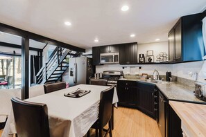 A modern kitchen with a dining area, featuring a built-in microwave, stove, and a large island with a sink. - Cozy Sunriver Retreat - SHARC Passes, Bike and BBQ (Sunriver)