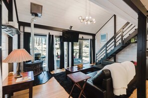 A cozy living room with a fireplace, a television, and a staircase leading to an upper level. - Cozy Sunriver Retreat - SHARC Passes, Bike and BBQ (Sunriver)