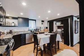 A compact kitchen with a dining area, equipped with a stove, sink, and refrigerator. - Cozy Sunriver Retreat - SHARC Passes, Bike and BBQ (Sunriver)