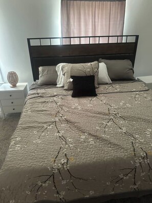 Ein Bett mit strukturierter Bettdecke, einem dunklen Kopfteil und mehreren Kissen.