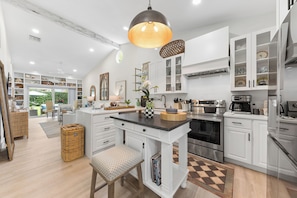 A modern kitchen with white cabinetry, a central island, and stainless steel appliances.