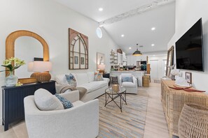 A modern living room with a sofa, armchairs, a coffee table, and a television.