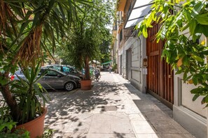 A narrow urban street with parked cars, a bicycle, and potted plants lining the sidewalk. - Charming, tastefully furnished apartment of 50 sqm, able to accommodate up to 4 guests, located on the first floor of a building with a lift (accessible via a few steps). The property is situated in a quiet district offering all amenities and excellent c (Palermo)
