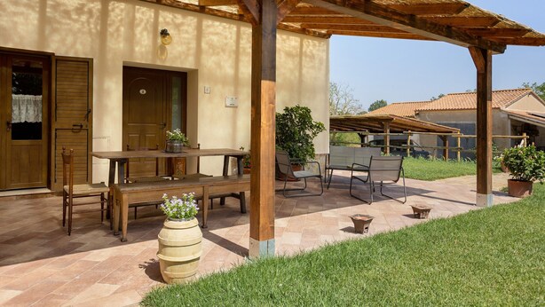 A covered outdoor seating area with wooden furniture and potted plants. - Holiday Home 'Appartamento 3' with Shared Garden, Wi-Fi and Air Conditioning (Montiano)