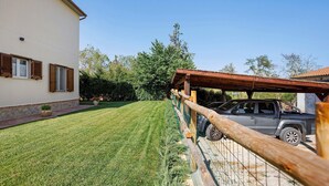 A well-maintained lawn, a wooden fence, and a parked vehicle in front of a building with a tiled roof. - Holiday Home 'Appartamento 3' with Shared Garden, Wi-Fi and Air Conditioning (Montiano)