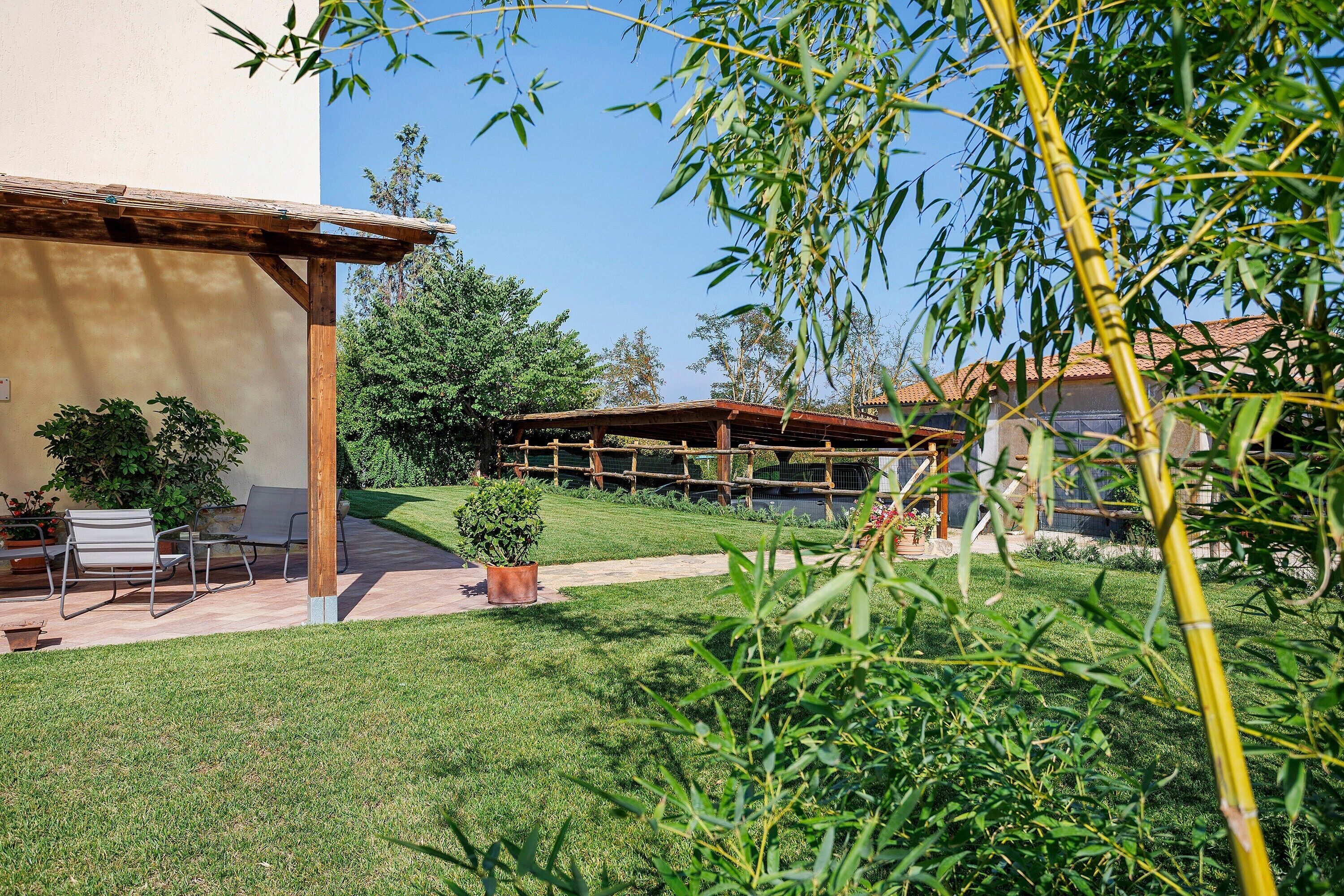 A patio area with outdoor furniture, a pergola, and a well-maintained lawn.