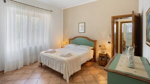 A hotel room with a bed, a nightstand, a lamp, a framed picture, and a vase on a table. - Holiday Home 'Appartamento 3' with Shared Garden, Wi-Fi and Air Conditioning (Montiano)