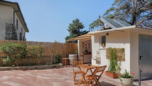 Un patio con una mesa y sillas de madera, un muro de piedra y una cerca de madera.