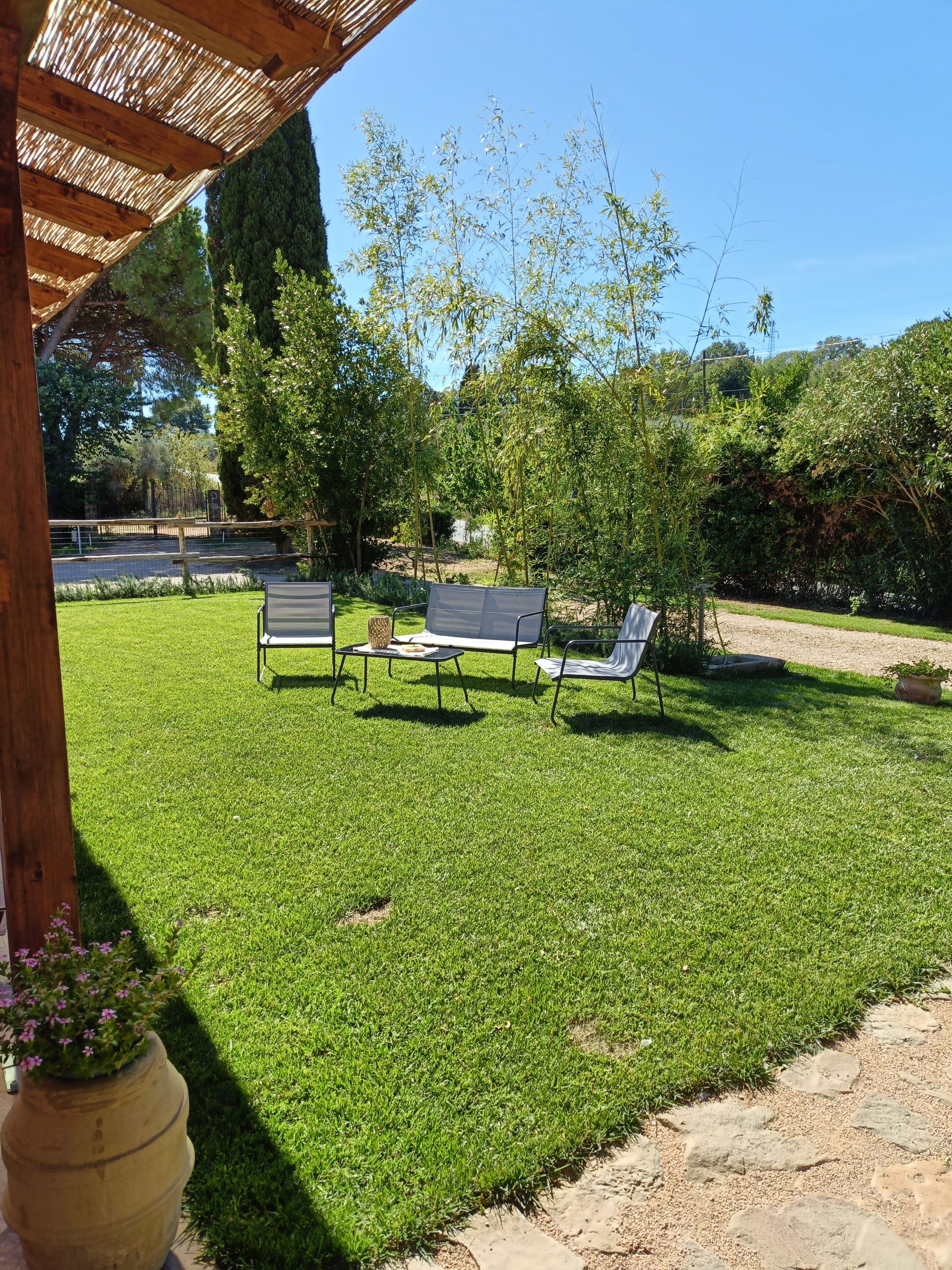 Une pelouse bien entretenue, agrémentée d’un espace extérieur aménagé avec des sièges et d’une structure en forme de pergola.