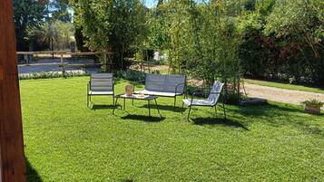 Un césped bien cuidado con mobiliario exterior y una pérgola.