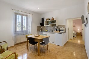 Una cocina compacta con una mesa de comedor, sillas y electrodomésticos básicos.