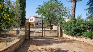 Un ingresso recintato con un muro in pietra, un cancello metallico e cielo sereno.