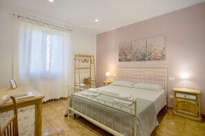 Ein Schlafzimmer mit einem Bett, Nachttischen, einem Kleiderschrank und einem Fenster mit Vorhängen.