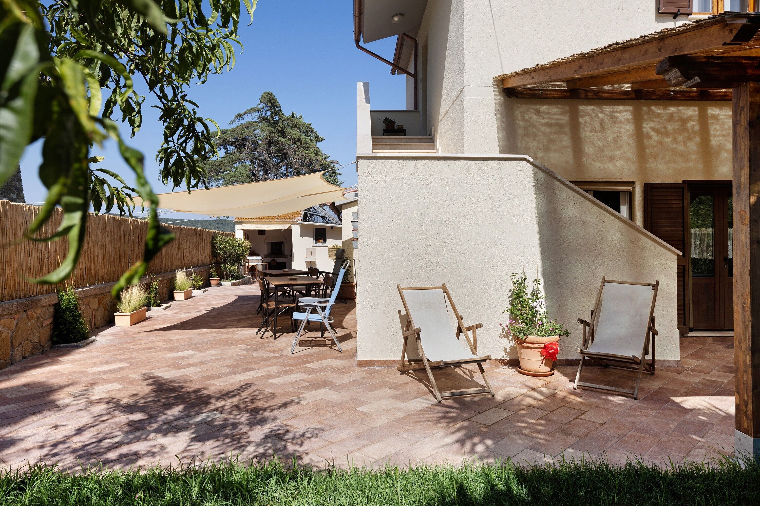 Un'area patio con tavolo e sedie, una recinzione in legno e una pianta in vaso.