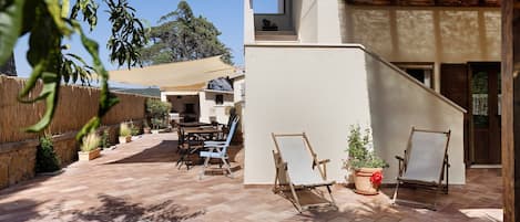A patio area with a table and chairs, a wooden fence, and a potted plant.