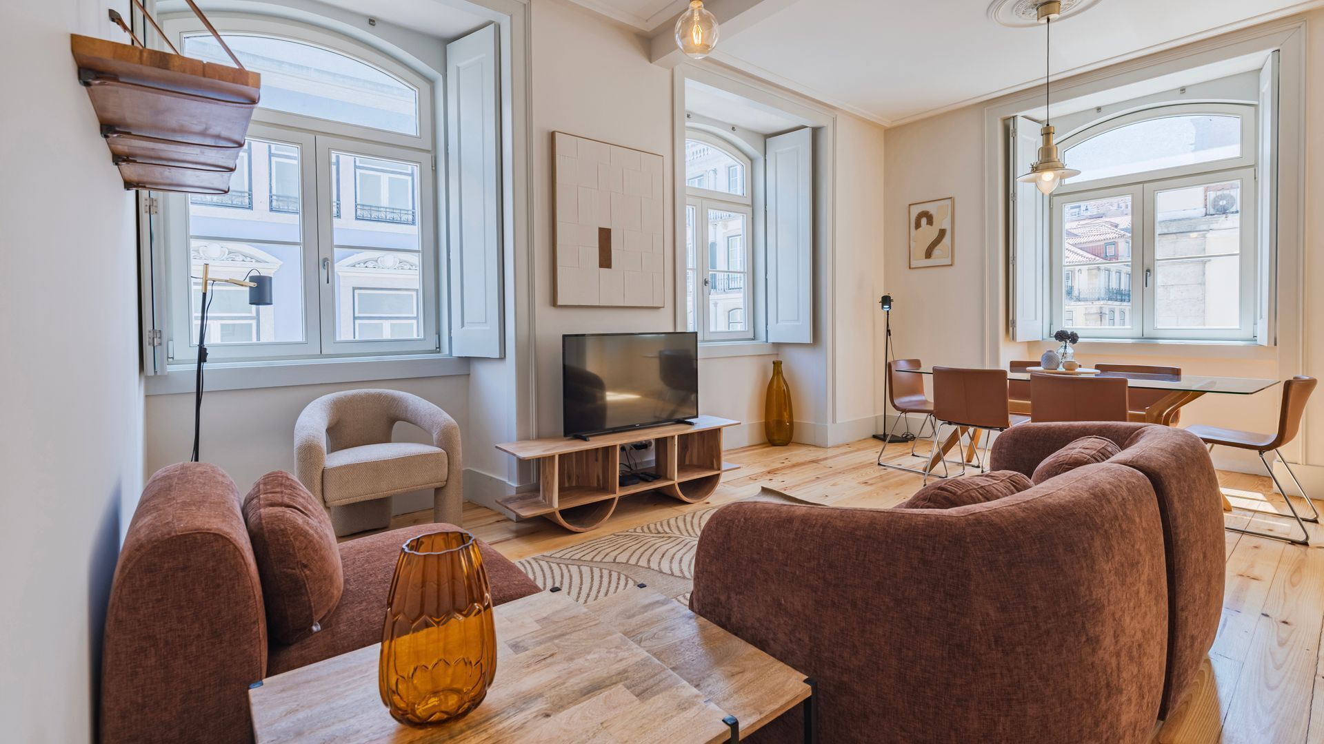 A modern living room with a sofa, TV, and dining area.