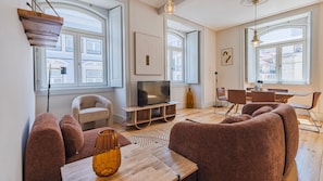 Ein modernes Wohnzimmer mit Sofa, Fernseher und Essbereich.