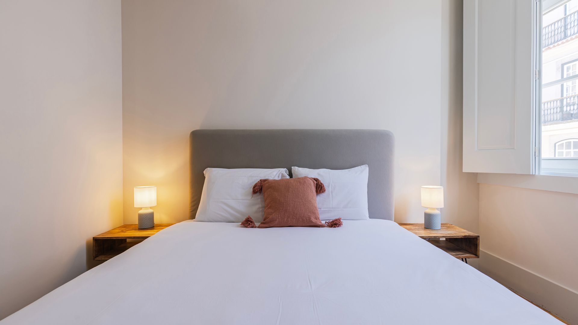 Habitación de hotel con cama, dos mesitas de noche y dos lámparas.