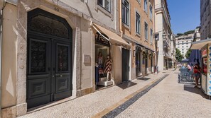 Eine Kopfsteinpflasterstraße mit kleinen Geschäften, einem geschlossenen Laden und blauem Himmel.