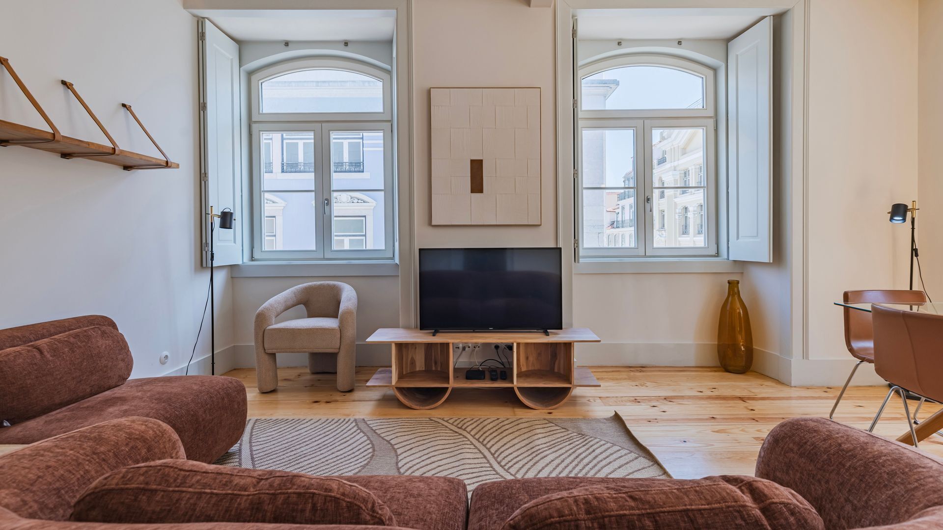 A living room with a flat-screen TV, a sofa, a chair, and a wooden coffee table.