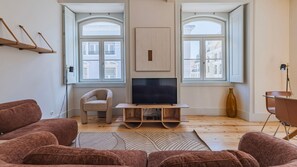 A living room with a flat-screen TV, a sofa, a chair, and a wooden coffee table. - Downtown 2BR in Santa Justa by LovelyStay (Lisboa)