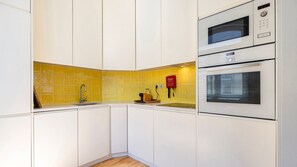 Eine Küche mit weißen Schränken, einer gelben Spritzschutzwand und zwei Bosch-Backöfen.