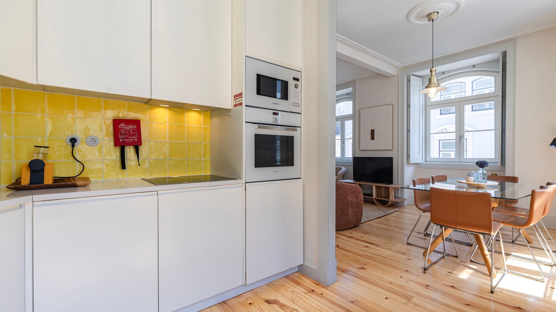 Una cucina moderna con mobili bianchi, uno schienale giallo e un forno Bosch.