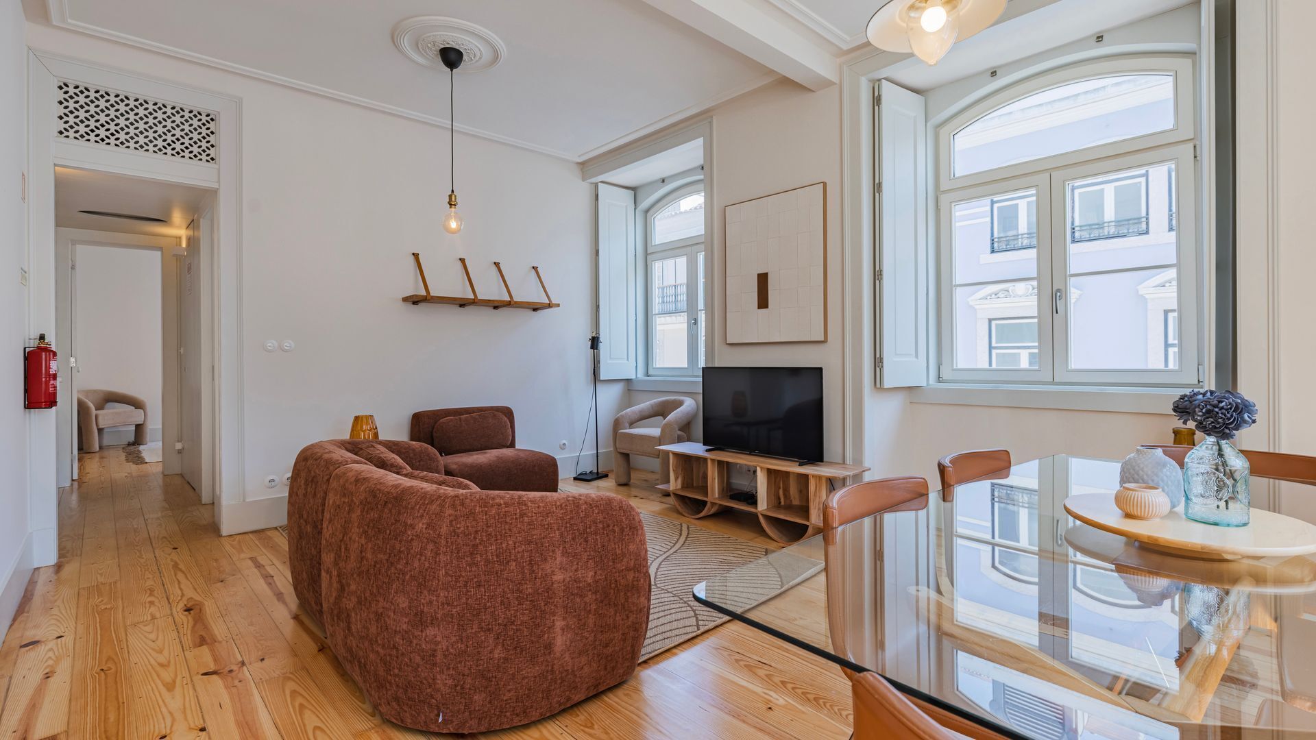 Een moderne woonkamer met een bank, tv en een eethoek met tafel en stoelen.
