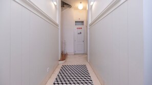 Passadís estret amb terra de pissos enquadernats que condueix a una porta amb un símbol de reciclatge.