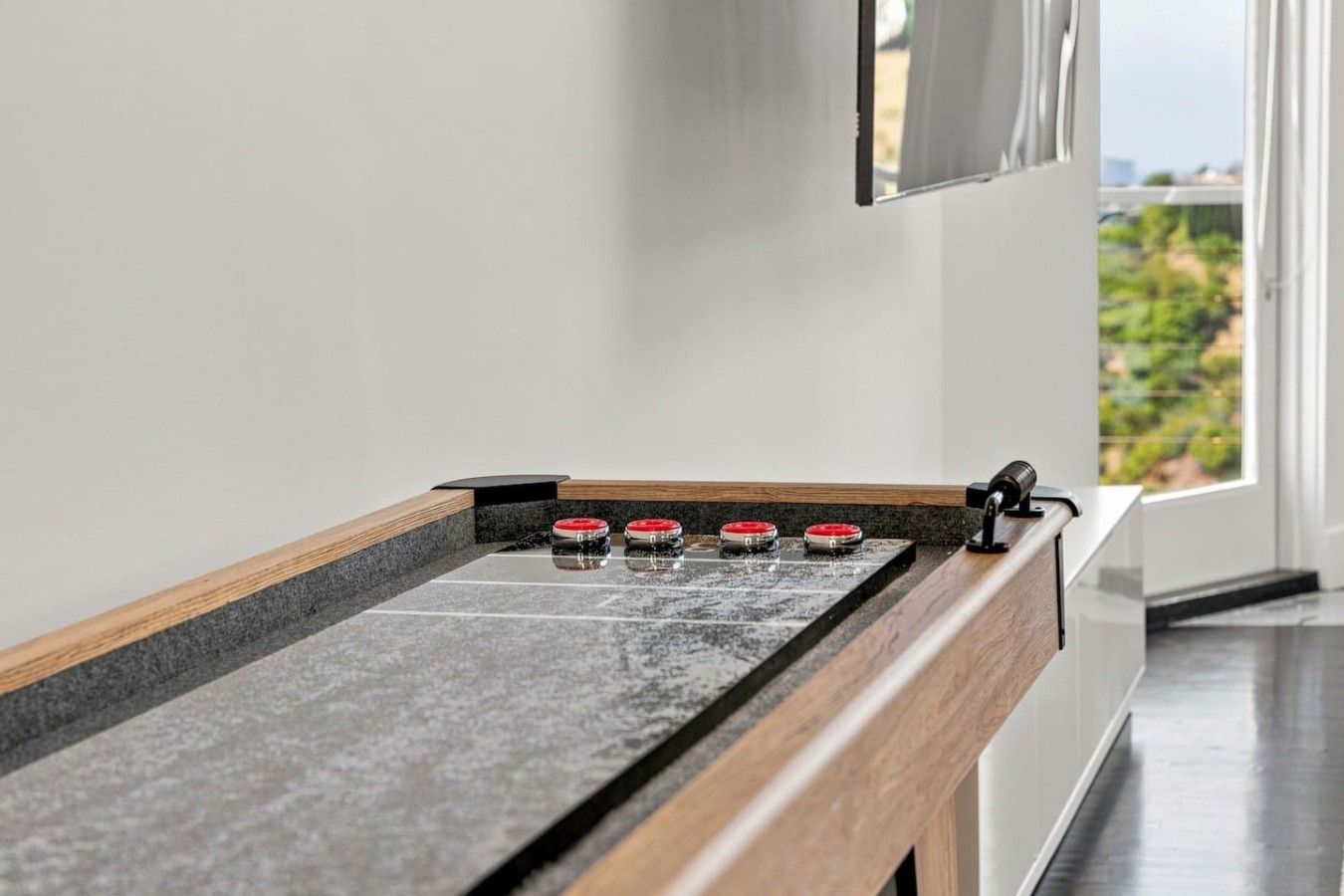 Cocina moderna con encimera de granito, estufa integrada y ventana con vistas a un paisaje verde.