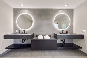 A modern bathroom with two sinks, a central mirror, and a towel rack.