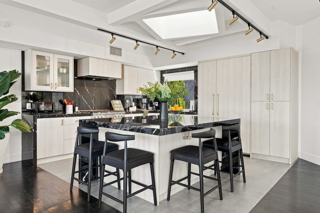 A modern kitchen with a central island, bar stools, and a skylight.
