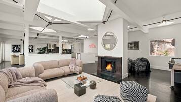 Una sala de estar moderna con chimenea, un sofá, una mesita de centro y un taburete a cuadros.