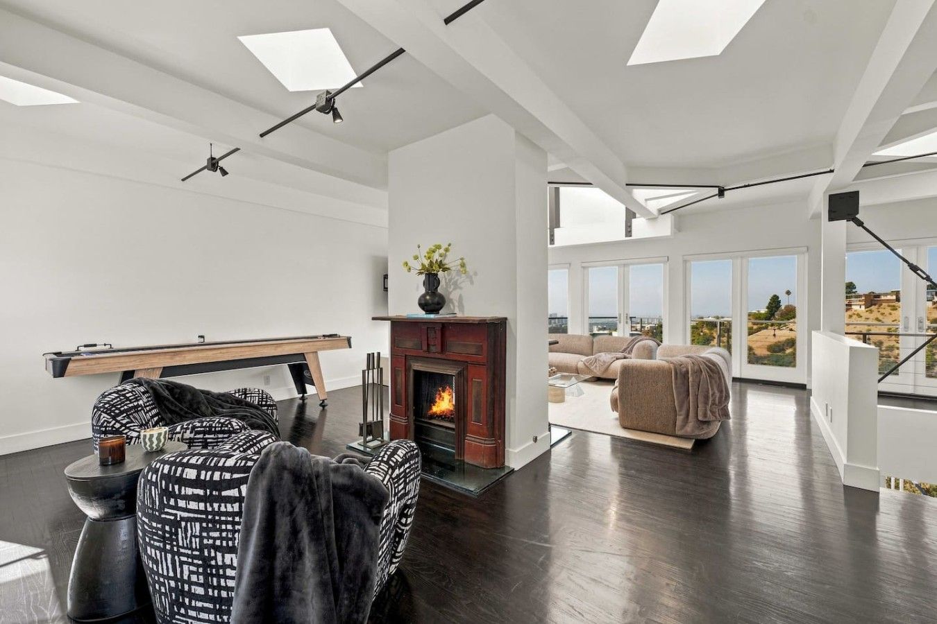 A modern living room with a fireplace, a pool table, and a view of the outdoors.