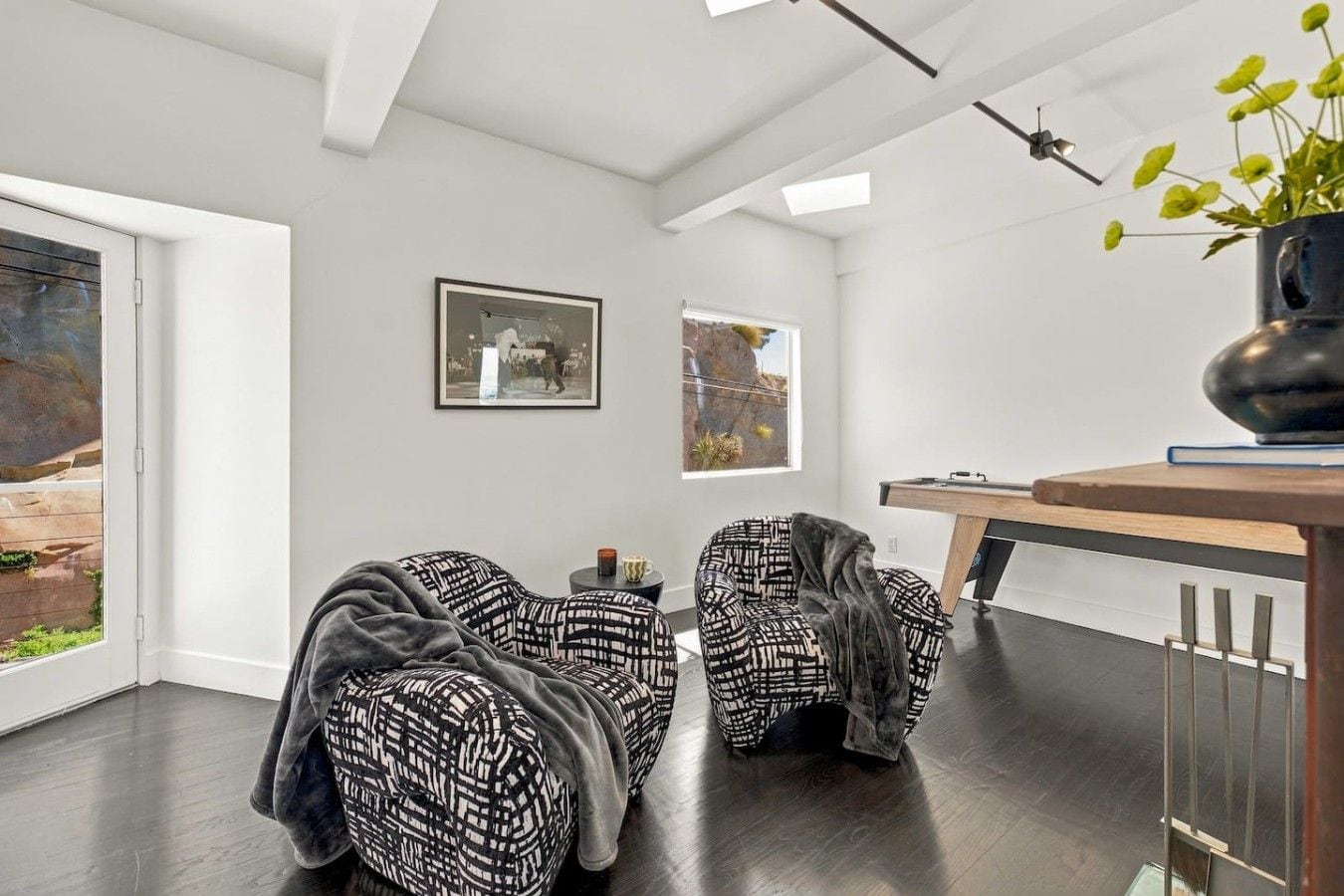 Una sala moderna con dos sillones estampados, una mesa de centro y una mesa de billar.