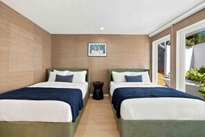 A hotel room with two beds, a small side table, and a picture on the wall.