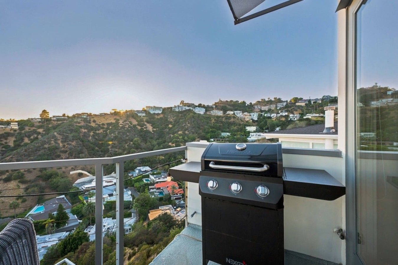 A balcony with a barbecue grill overlooking a residential area.