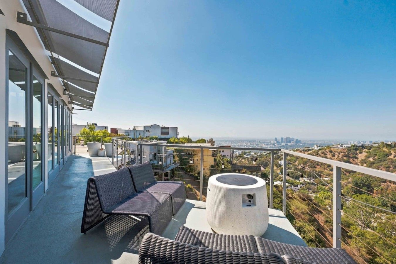 A rooftop terrace with outdoor seating, a fire pit, and a city view.