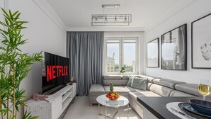 A modern living room with a flat-screen TV, a sofa, a coffee table, and a dining area. - Flat With Quiet Courtyard (Warsaw)