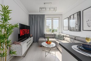 Ein modernes Wohnzimmer mit Flachbildfernseher, einer Couch, einem Couchtisch und einem Essbereich.