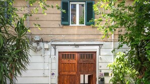 A building with a large wooden door, a window with green shutters, and a sign indicating a no parking zone. - GuestHost - Casa Tramonto Elegant Flat (Palermo)