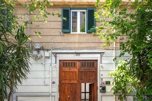 A building with a large wooden door, a window with green shutters, and a sign indicating a no parking zone. - GuestHost - Casa Tramonto Elegant Flat (Palermo)