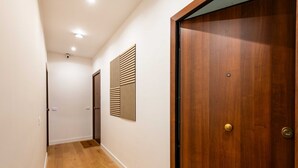A hallway with wooden flooring, a wooden door, and a wall-mounted panel. - GuestHost - Casa Tramonto Elegant Flat (Palermo)