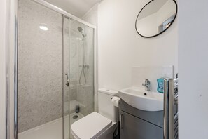 Une salle de bain avec une douche à parois de verre, des toilettes, un lavabo et un miroir.