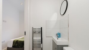 A bathroom with a white sink, a mirror, and a towel rack. - 4 bed, 4 en-suite house (Warrington)